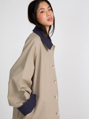 A model showcases a stylish beige MEOTINE coat with a navy collar and cuffs, exuding a modern and chic vibe.