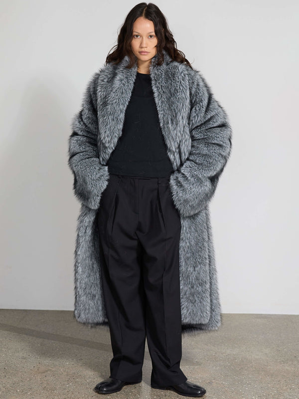 A model showcases a luxurious gray faux fur coat by MEOTINE, paired with black trousers, exuding elegance and warmth.