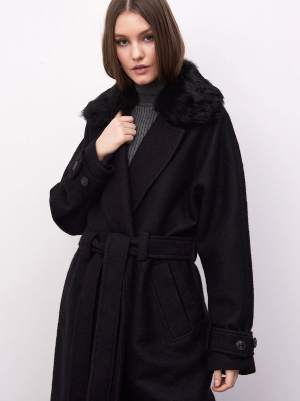 A model showcases a stylish black coat with a faux fur collar, featuring a belted waist, perfect for a chic winter look by MEOTINE.