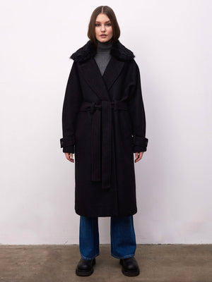 A model showcases a stylish black coat with a fur collar, paired with a gray turtleneck and wide-leg jeans, by MEOTINE.