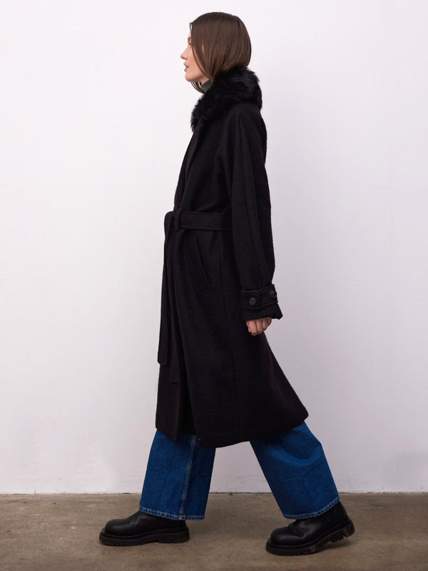 A model showcases a stylish black coat with a fur collar, paired with wide-leg jeans and chunky boots, embodying MEOTINE's chic aesthetic.