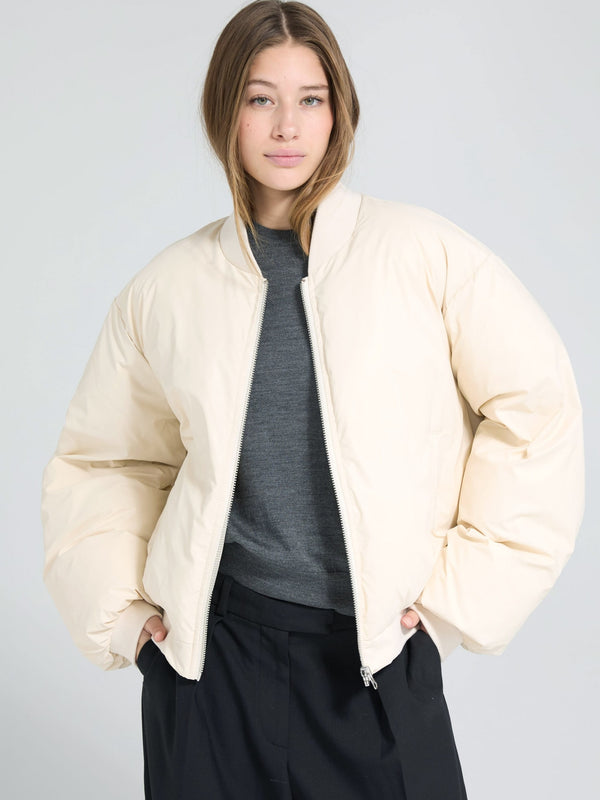 A model wears a stylish cream-colored bomber jacket, showcasing a relaxed fit and soft fabric, perfect for casual outfits. MEOTINE.