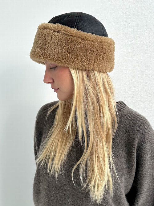 Stylish woman wearing a brown fur-lined hat with a black leather top, showcasing MEOTINE's chic winter accessory.