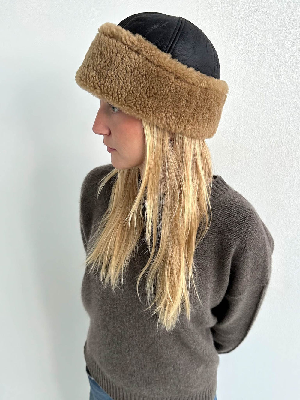 Stylish woman wearing a brown fur-lined hat with a black leather top, showcasing MEOTINE's chic winter accessory.