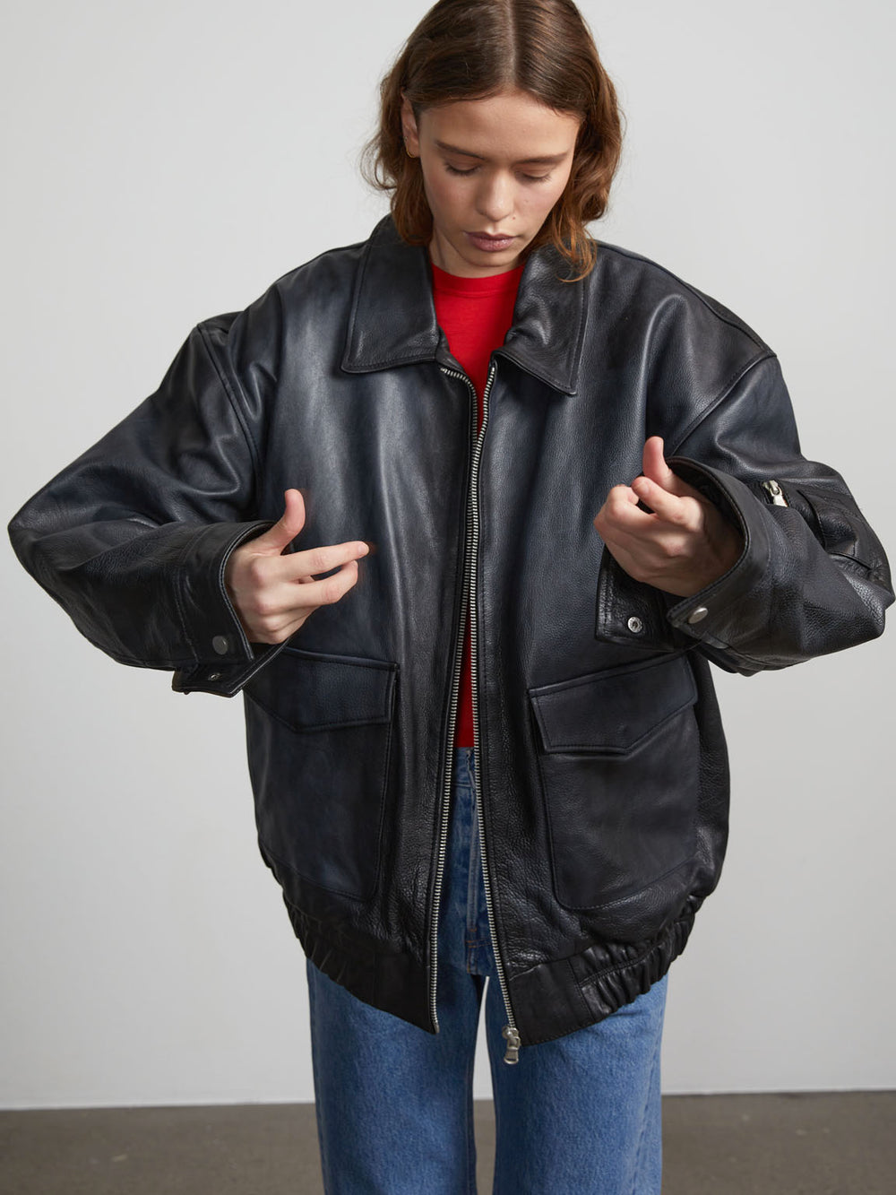 A model showcases a stylish black leather jacket from MEOTINE, paired with a turtleneck and trendy sunglasses.