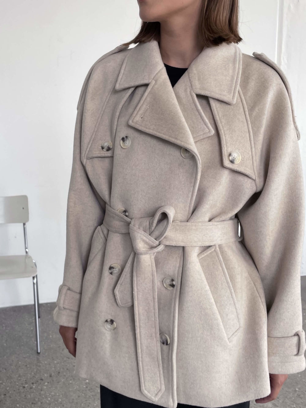 A stylish beige trench coat with a belted waist, featuring large buttons and a relaxed fit, perfect for a chic look by MEOTINE.