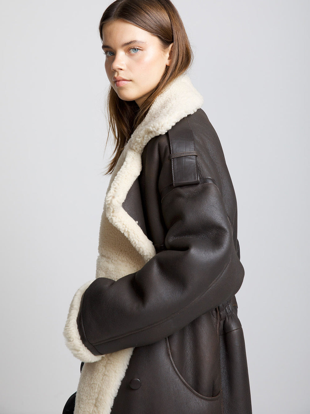A model showcases a stylish brown shearling coat with a cozy cream lining, perfect for a chic winter look by MEOTINE.