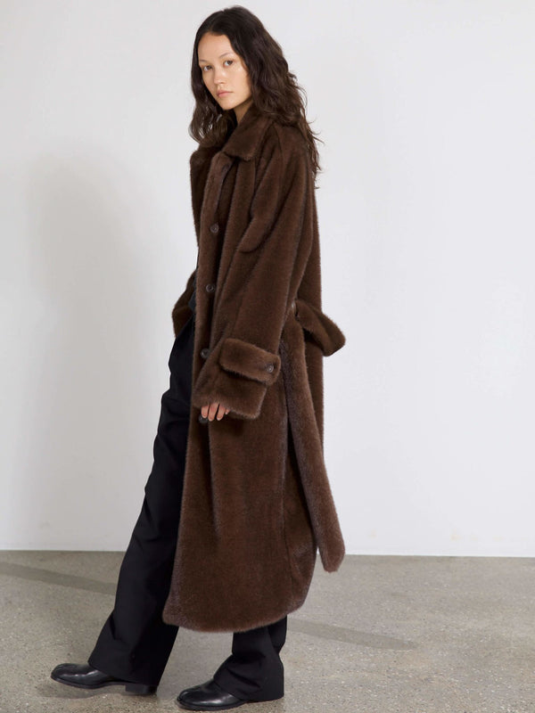 A model showcases a luxurious brown oversized coat by MEOTINE, featuring a classic collar and button closure, styled with black pants.
