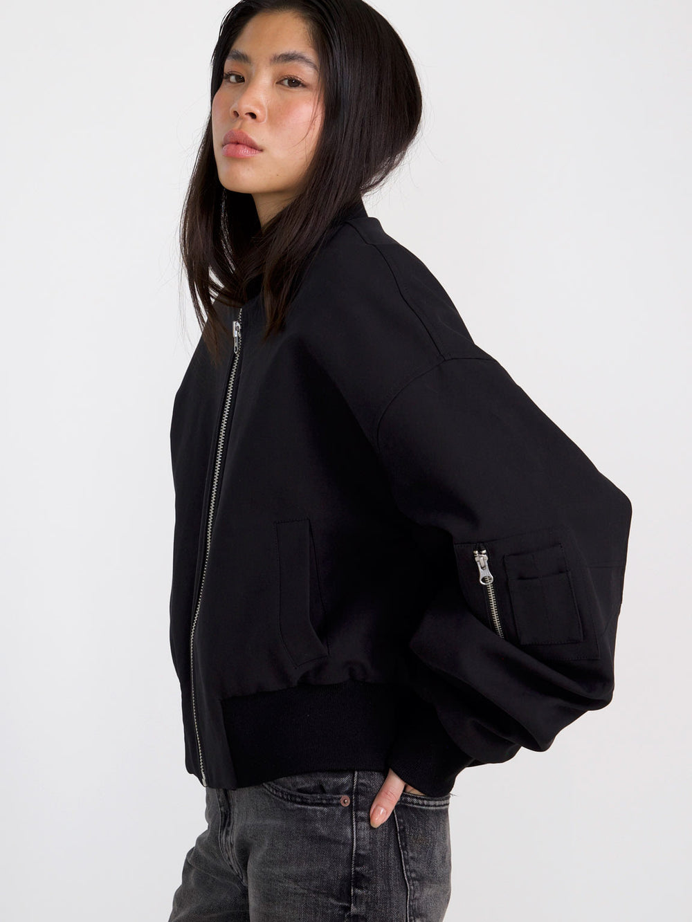 A model wears a stylish black bomber jacket with a zip front and oversized sleeves, showcasing MEOTINE's modern design.