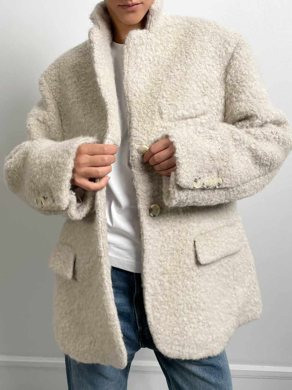 Cozy beige oversized jacket with a textured finish, featuring a notched collar and buttoned front, styled with a simple white tee. MEOTINE.