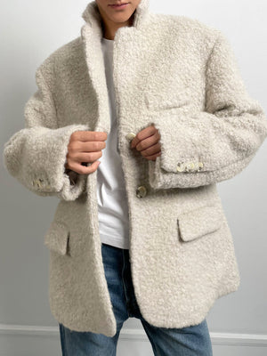 Cozy beige oversized jacket with a textured finish, featuring a notched collar and buttoned front, styled with a simple white tee. MEOTINE.