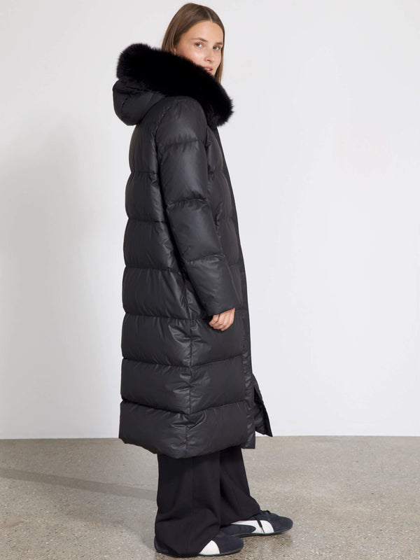 A model wearing a long black puffer coat with a fur-lined hood, showcasing MEOTINE's stylish winter outerwear.