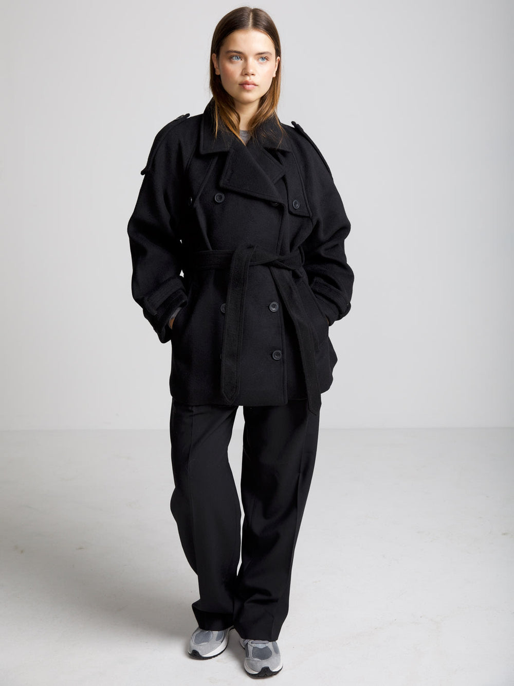 A model wears a stylish black oversized coat with a belt, showcasing a chic and modern look by MEOTINE.