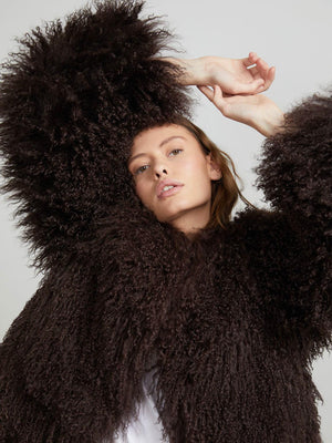A model poses in a fluffy, dark brown MEOTINE coat, showcasing its textured sleeves and stylish silhouette against a neutral background.