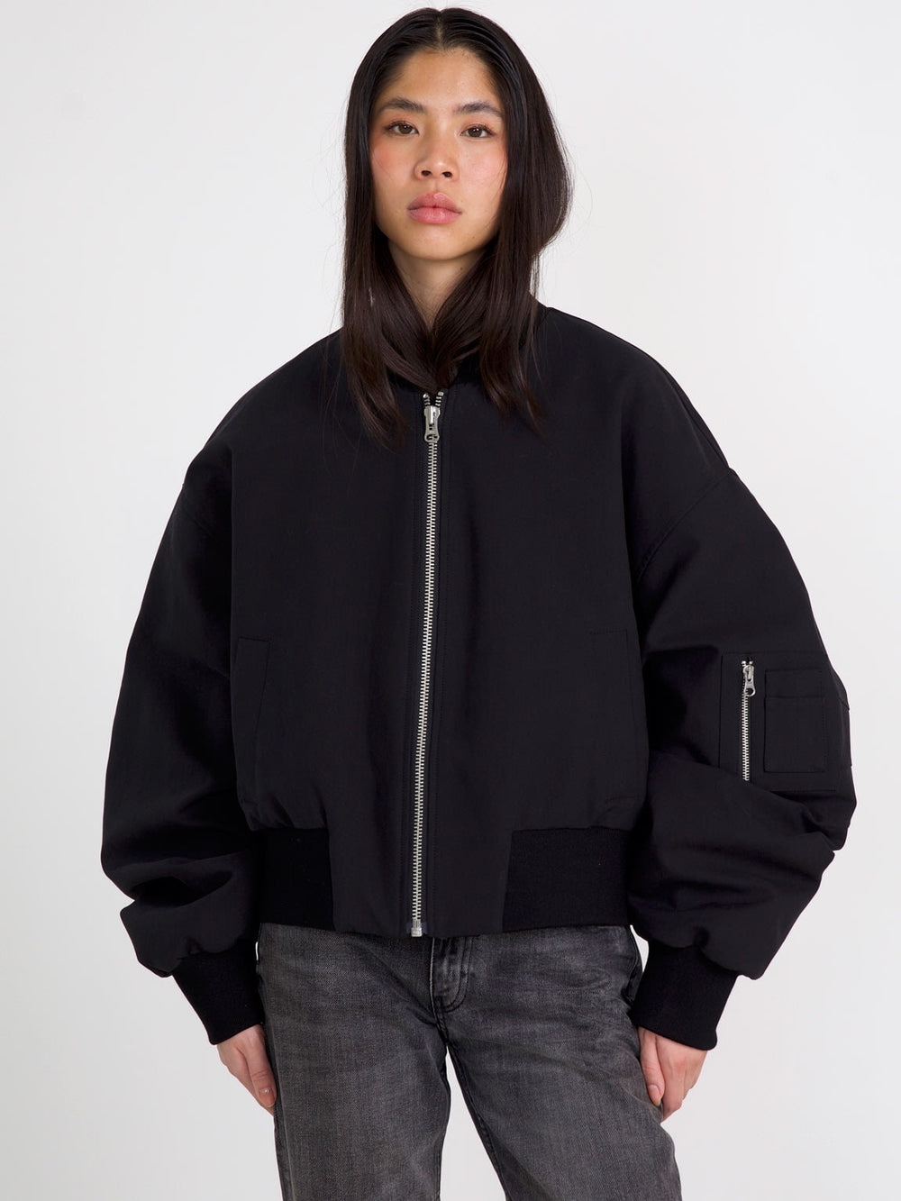 A model wears a stylish black bomber jacket with a zip front and oversized sleeves, showcasing MEOTINE's modern design.