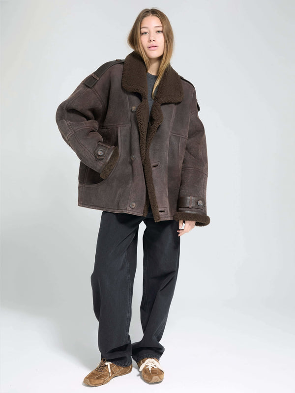 A model wears a cozy brown MEOTINE jacket with a large collar, paired with loose black pants and casual shoes.