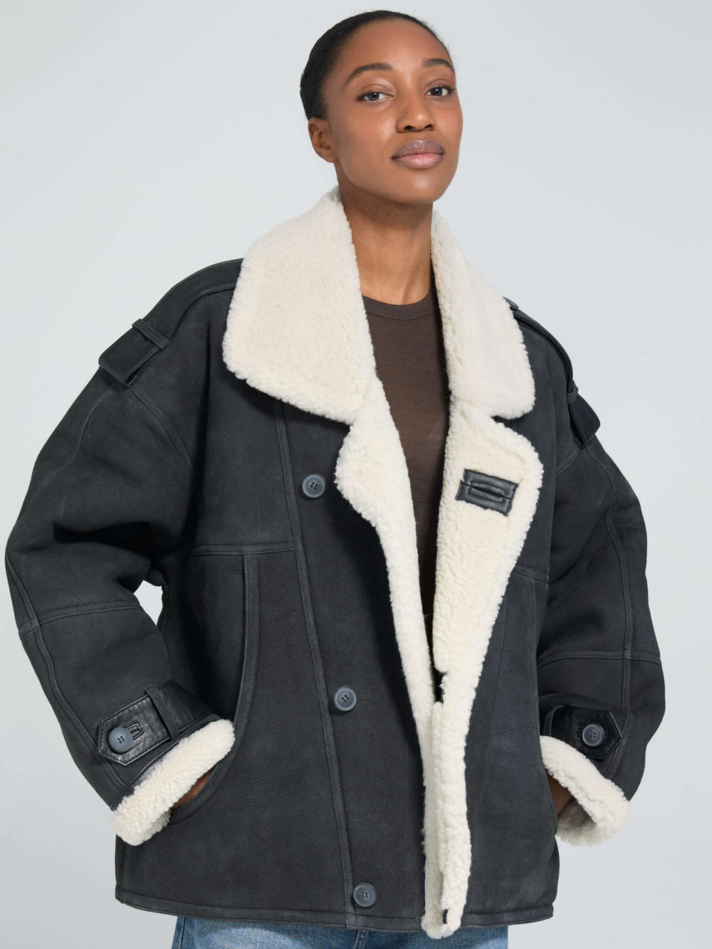 A model wears a stylish black MEOTINE jacket with a cozy white shearling collar, showcasing a relaxed fit and button details.