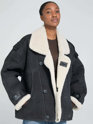 A model wears a stylish black MEOTINE jacket with a cozy white shearling collar, showcasing a relaxed fit and button details.