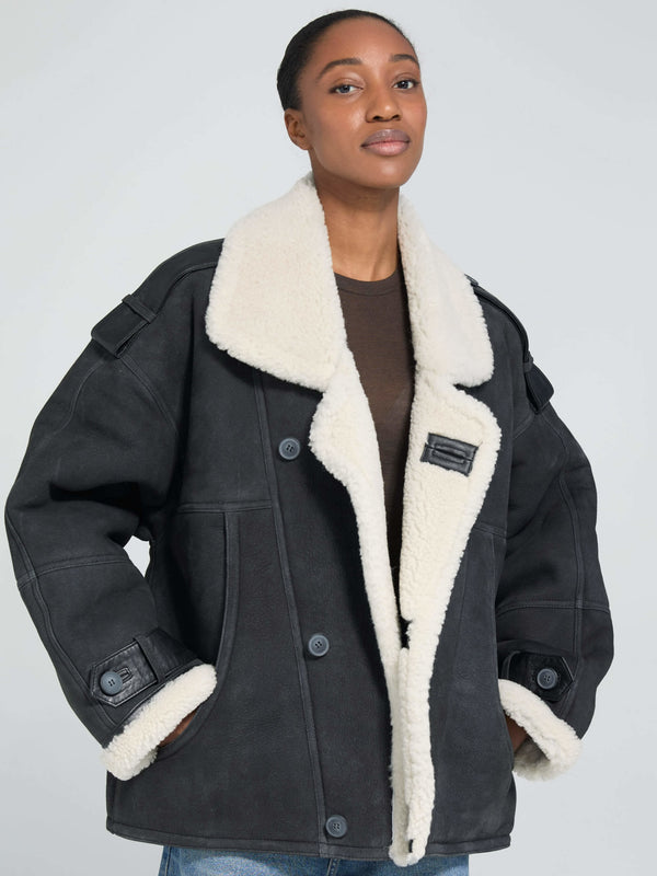 A model wears a stylish black MEOTINE jacket with a cozy white shearling collar, showcasing a relaxed fit and button details.
