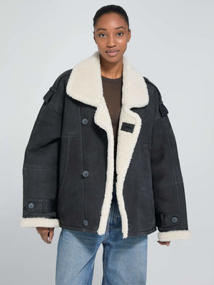 Oversized black jacket with a cozy cream shearling collar, featuring button closures and a relaxed fit, by MEOTINE.