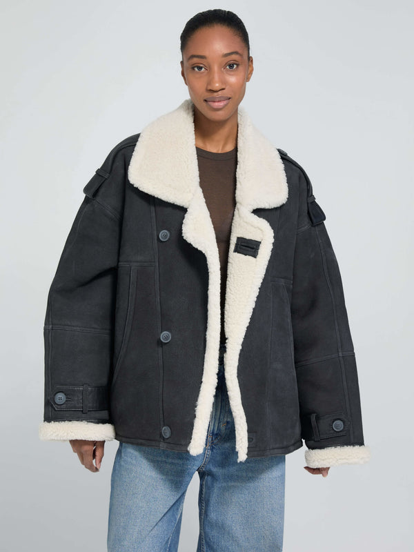 Oversized black jacket with a cozy cream shearling collar, featuring button closures and a relaxed fit, by MEOTINE.