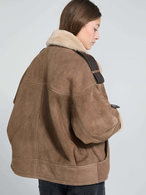 A model showcases a cozy brown MEOTINE jacket with a plush collar, styled casually against a light background.