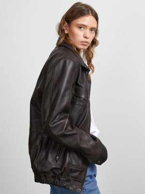 Stylish brown leather jacket with a relaxed fit, featuring zippered pockets and a cinched waist, perfect for a trendy look. MEOTINE.
