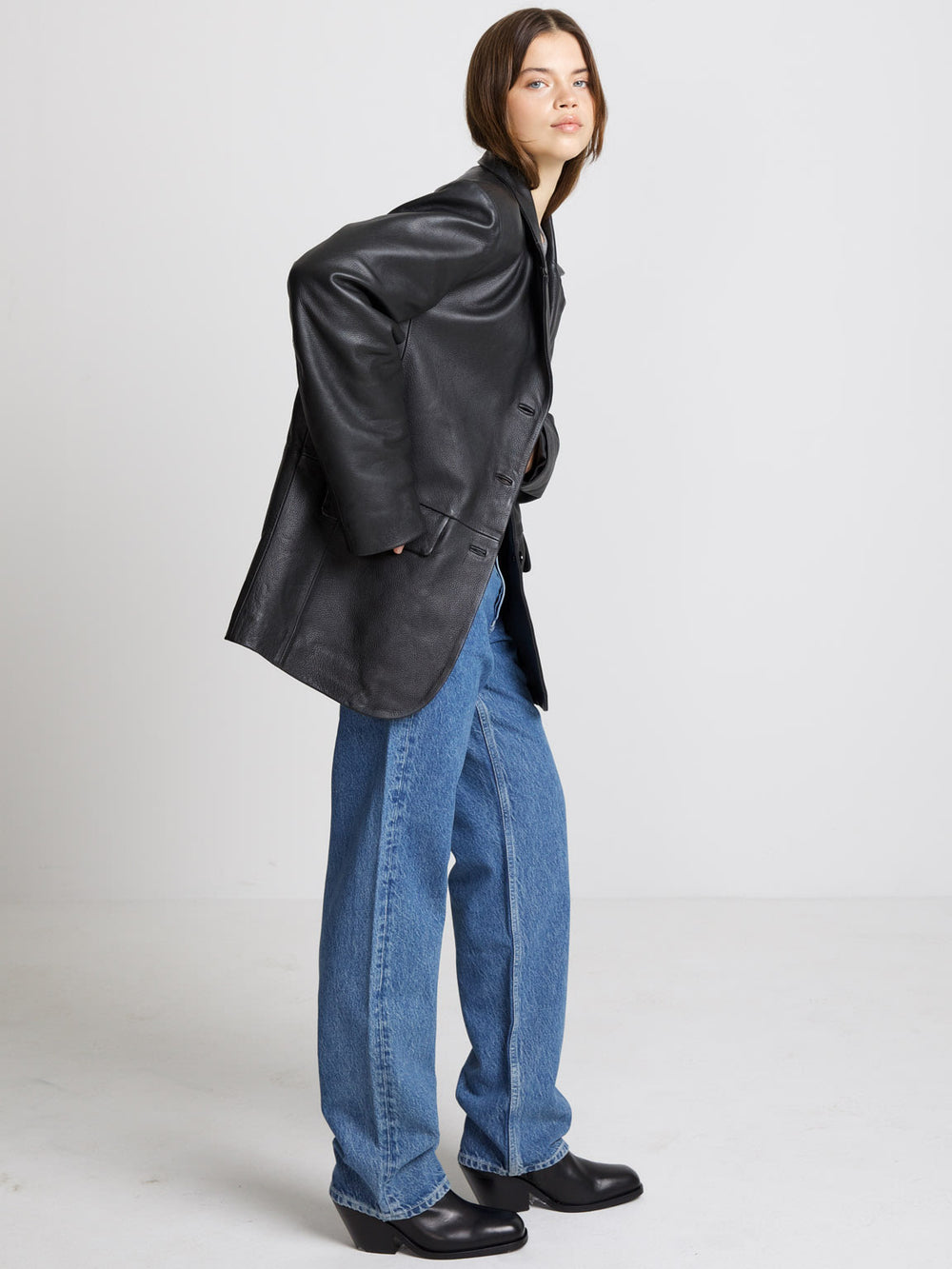 A model showcases a stylish oversized black leather blazer paired with a gray top and high-waisted jeans, embodying MEOTINE's chic aesthetic.