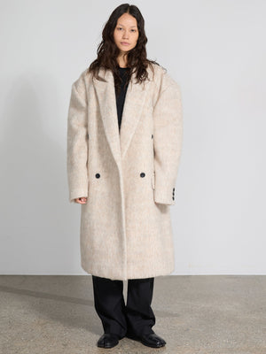 A model showcases a cozy, oversized cream coat with a soft texture, featuring a double-breasted design by MEOTINE.