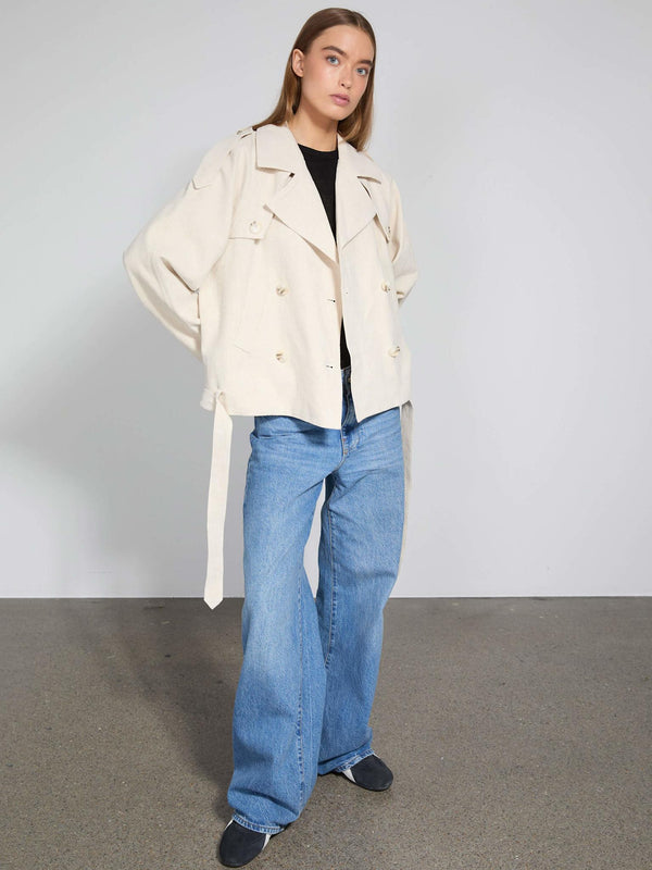 A model showcases a stylish beige MEOTINE jacket paired with loose blue jeans, exuding a modern, casual vibe.